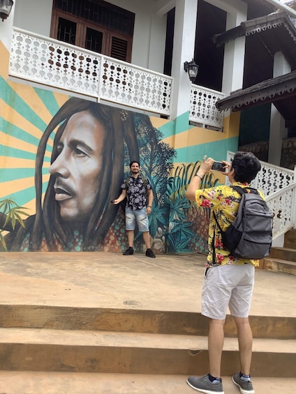 A person taking a photo of a mural on a building's exterior. 4