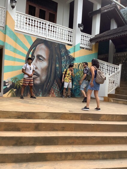 A group of people standing on a staircase in front of a building with a colorful mural. 3