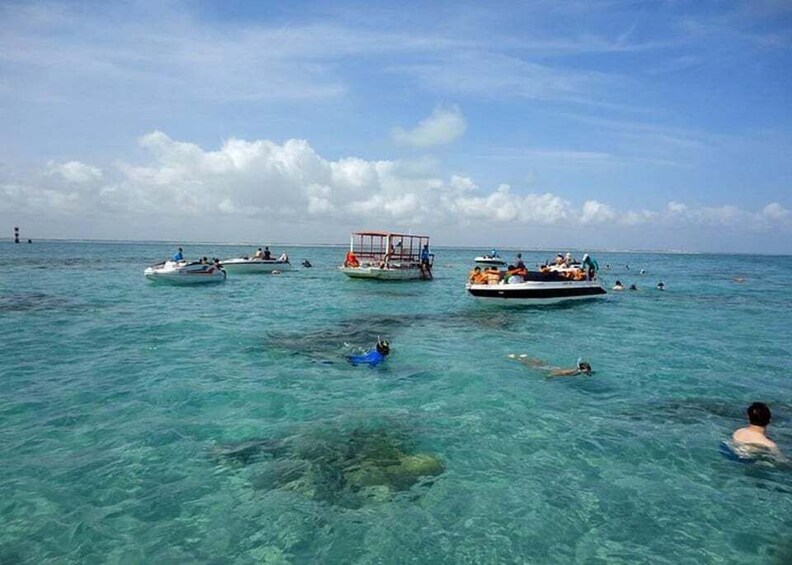 A clear blue sea with several boats and people swimming. 5