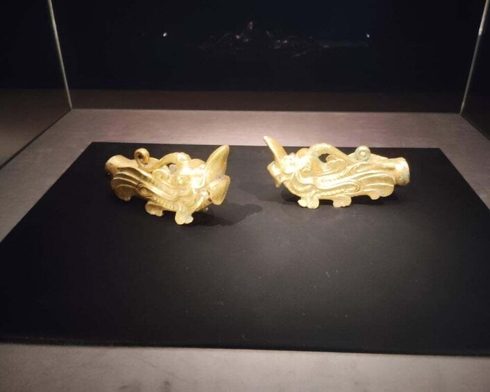 Two golden sculptures on a black display surface. 5