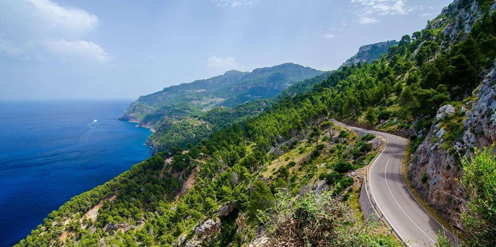 A winding mountain road with dense green forests and a coastline. 4