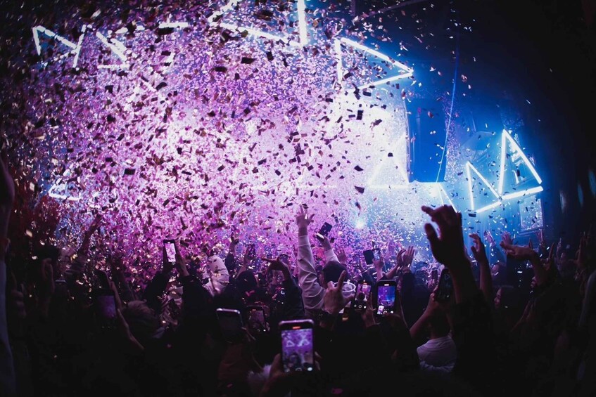 A concert with a crowd, stage lighting, and confetti. 3