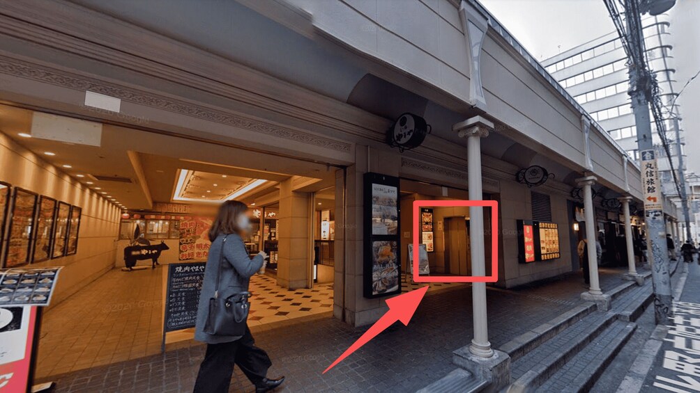 A street with a building entrance, a person walking, and a red arrow pointing to a door. 5