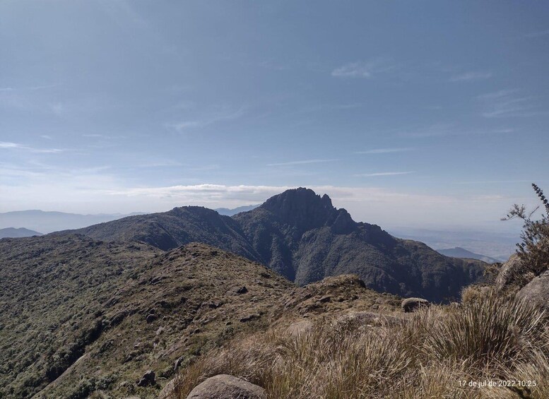 A mountainous landscape with a prominent peak, rolling hills, and sparse vegetation. 3