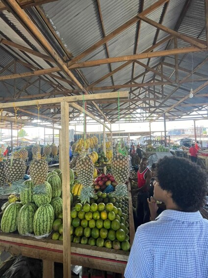 A market stall with various fruits like pineapples, watermelons, and bananas. 4