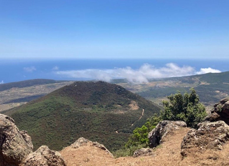 A mountainous landscape with a clear sky, a winding road, and a distant view of the ocean. 2