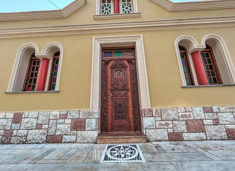 A building with a decorative wooden door, arched windows, and a stone base. 1