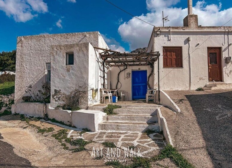 A traditional white building with a blue door, stone steps, and a wooden pergola. 5