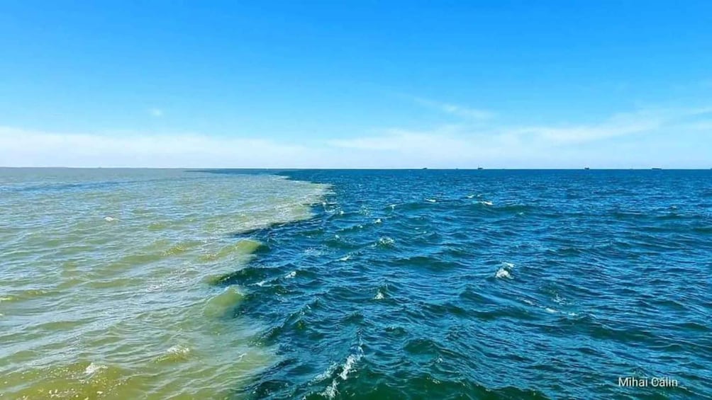 A coastal scene with a clear sky, calm sea, and a visible shoreline. 2
