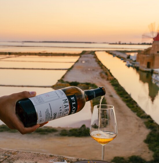 A person pouring wine from a bottle into a glass. 5