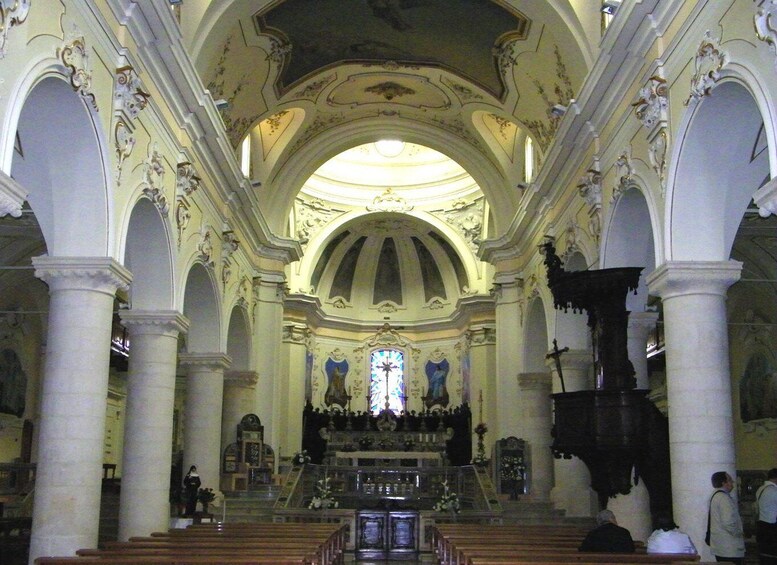 An ornate church interior with high ceilings, arched columns, and a central altar. 5