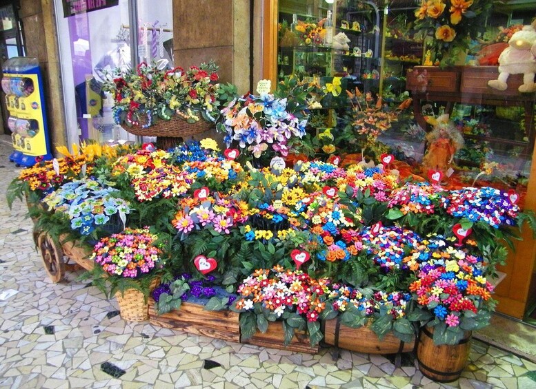 A flower shop with a variety of colorful flowers displayed in baskets and pots. 2