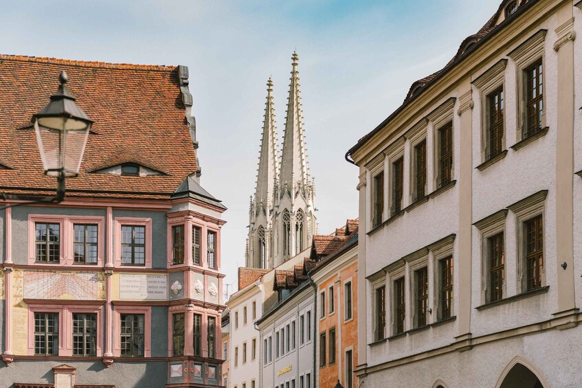 A street with historic buildings, a church spire, and a street lamp. 2