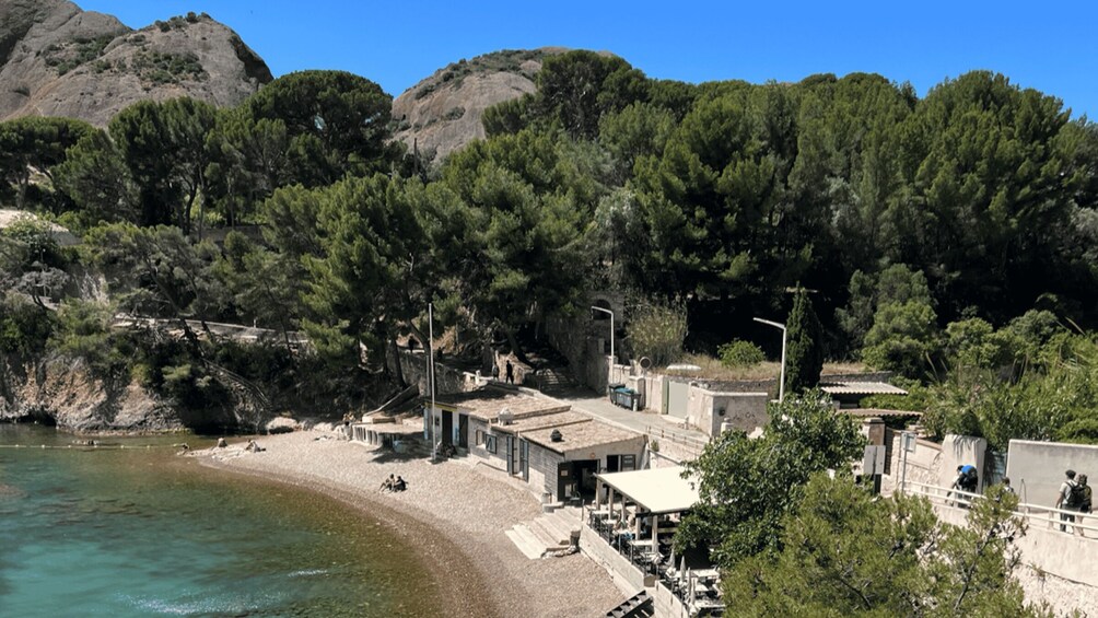 A coastal town with buildings, a beach, and dense forested hills. 2