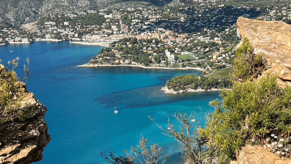 A coastal town with a clear blue sea, a small island, and a rocky cliff. 4