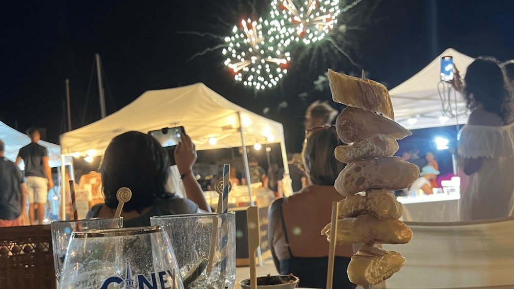A festive outdoor event with people, a tent, and a firework display. 3