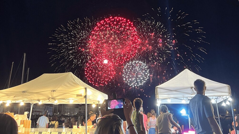 A night scene with fireworks and people under tents. 5