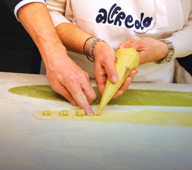 A person using a piping bag to apply a yellow substance onto a flat surface. 1