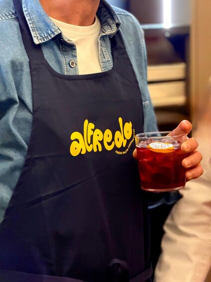 A person wearing a denim shirt and a black apron with yellow text. 4