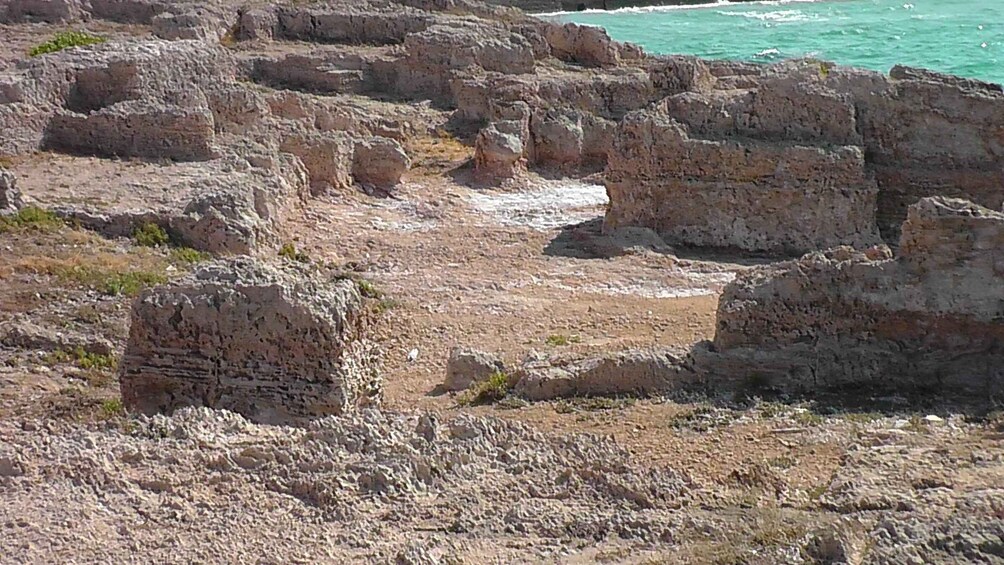 A rocky coastal landscape with layered sedimentary formations and a clear view of the ocean. 2