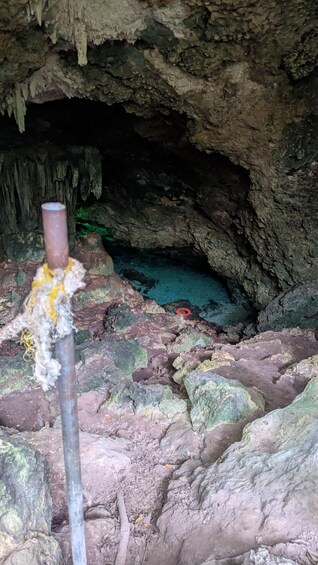 A cave interior with stalactites, a pipe, and a red ring on the ground. 5