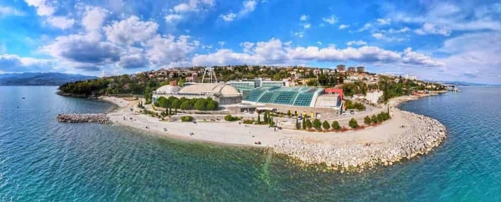 A coastal town with a beach, a large stadium, and a rocky peninsula. 5