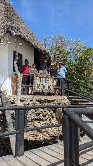 A group of people standing on a wooden platform with a sign that reads 'THE ROCK'. 4