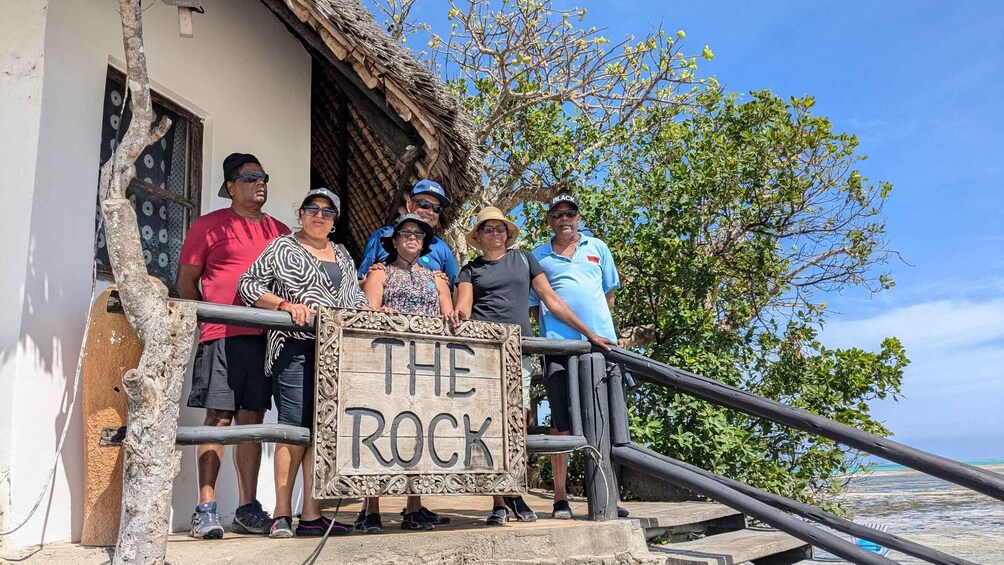 A group of people standing on a staircase with a sign that reads 'THE ROCK'. 3