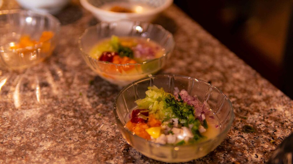 Three glass bowls on a granite countertop containing various chopped vegetables and herbs. 5