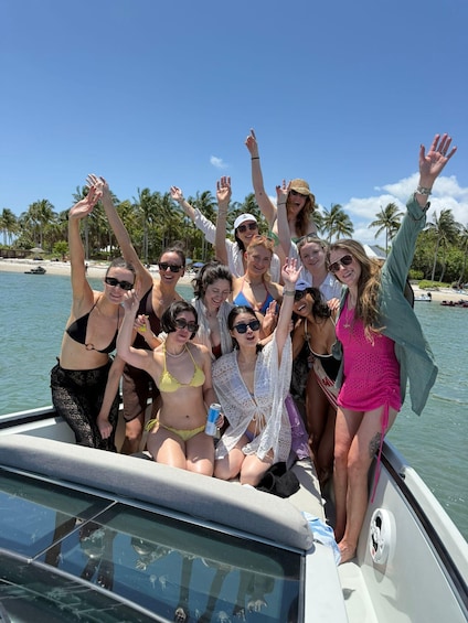 A group of people on a boat with palm trees and a beach in the background. 4