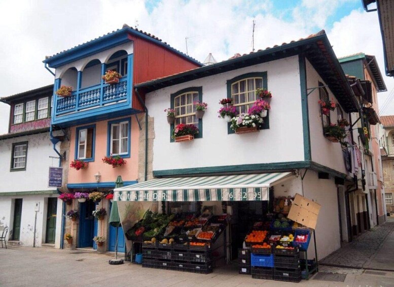 A colorful building with a balcony and flower boxes, a market stall with fruits and vegetables, and a cobblestone street. 5