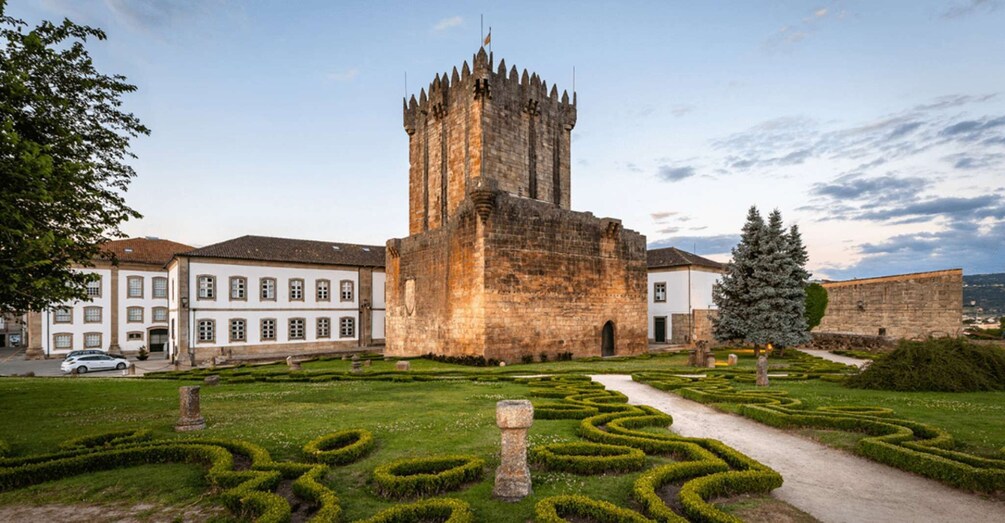A historic tower with a square base and a tall, narrow tower, surrounded by manicured gardens and white buildings. 2