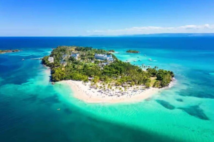 An island with a beach, clear turquoise waters, and lush greenery. 3