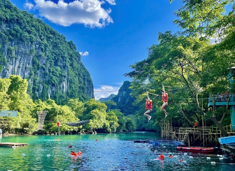 People jumping off a bridge into a river surrounded by lush greenery and mountains. 4