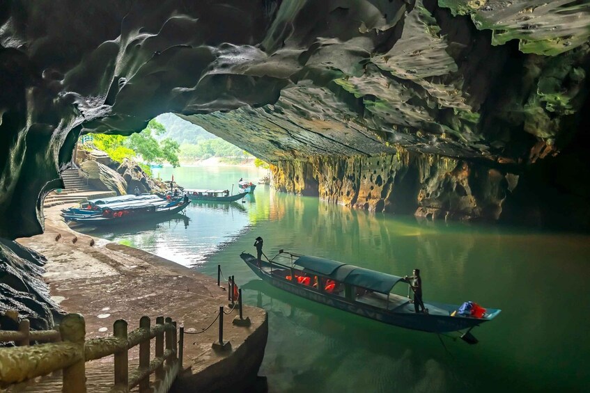 A cave opening with boats on a calm river. 1
