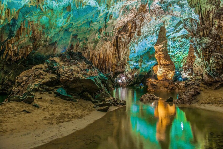 A cave with stalactites and stalagmites, a reflective pool, and a small boat. 5
