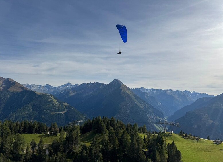A paraglider flying over a mountainous landscape with a clear sky. 2