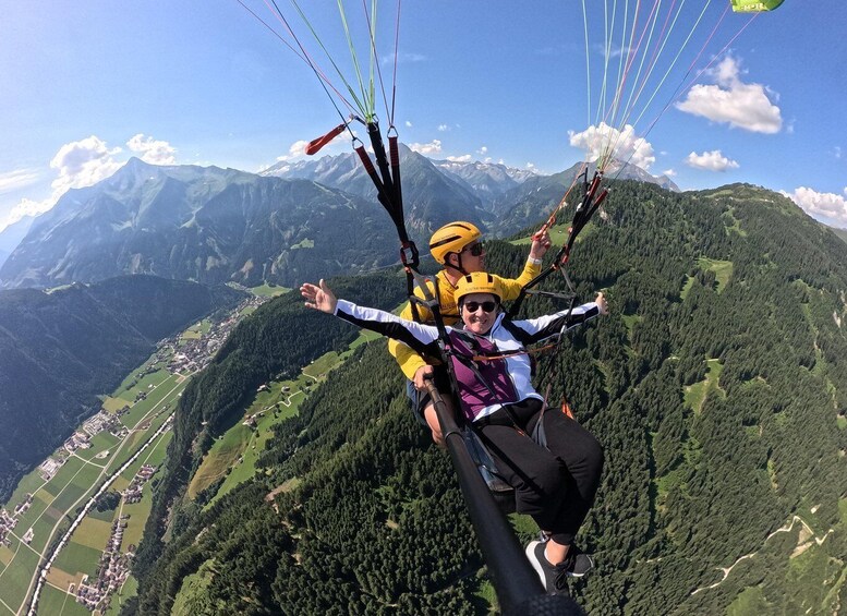 Two people paragliding with a mountainous landscape in the background. 5