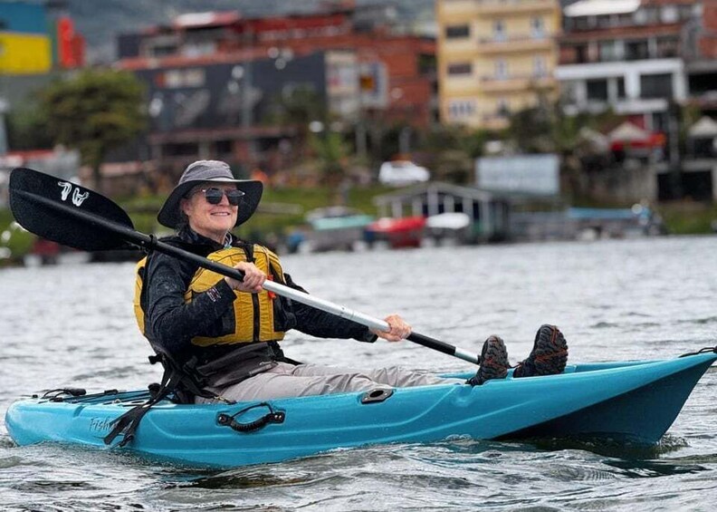 A person kayaking on a body of water with buildings in the background. 5