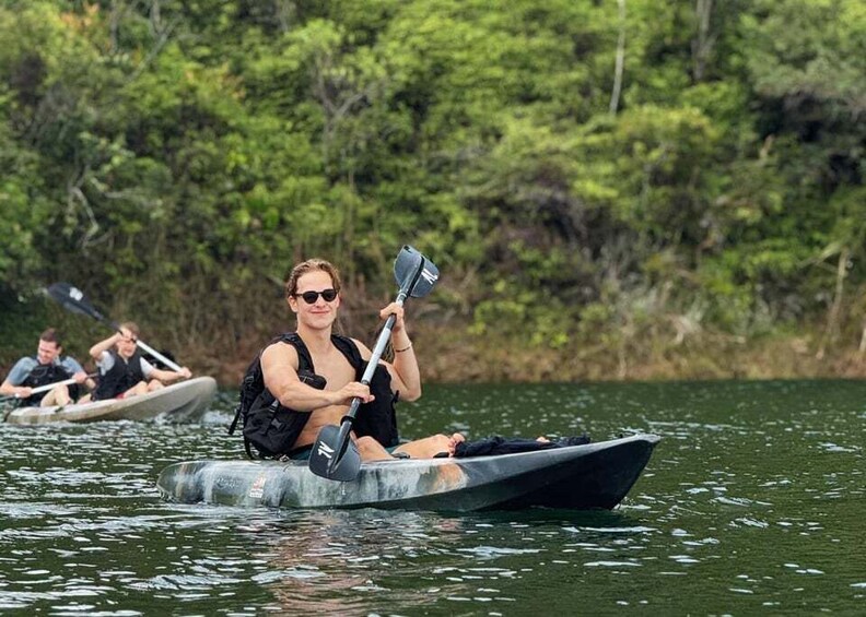 A person in a kayak on a body of water with trees in the background. 1