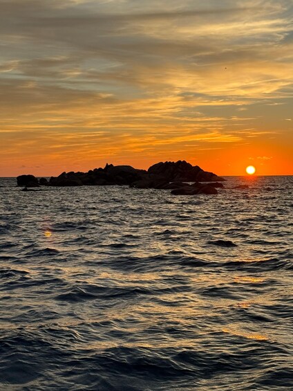 A sunset over the ocean with a rocky island silhouette. 5