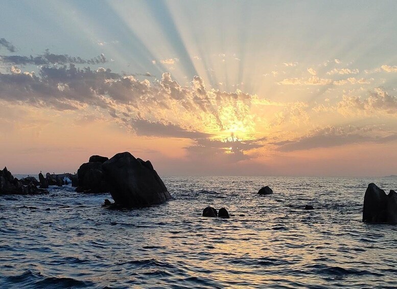 A sunset over the ocean with rocks in the foreground. 2