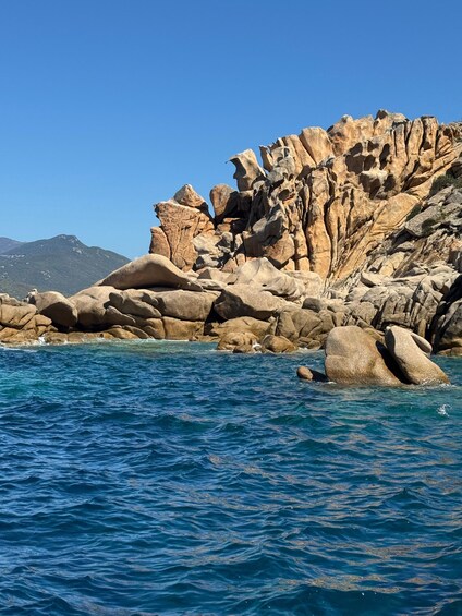 A rocky coastline with clear blue waters and a distant mountain. 4