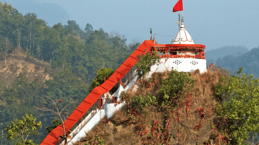 A temple on a mountain with a red roof and a flag. 2