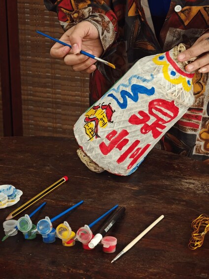 A person painting a bottle with colorful designs and Chinese characters. 1