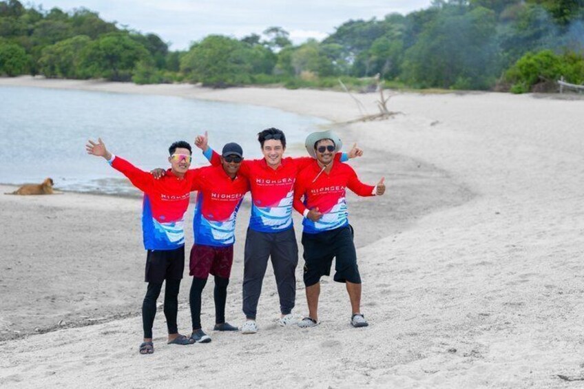 Four people standing on a sandy beach with their arms outstretched, wearing matching red and blue sports jerseys. 5