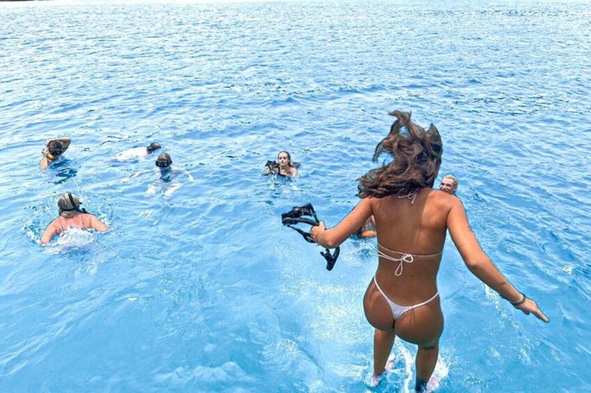 A person in a bikini standing in a pool with others swimming around. 2