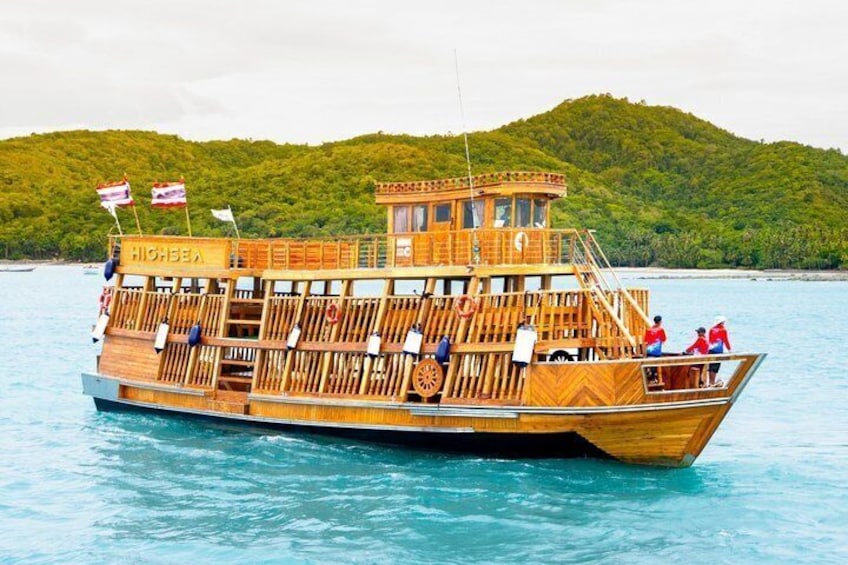 A wooden boat named 'HIGHESEA' on calm water with a forested hill in the background. 1