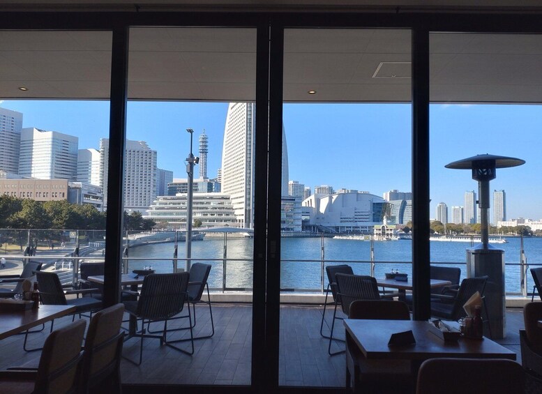 A waterfront restaurant with tables and chairs, overlooking a river with buildings and a bridge in the background. 5