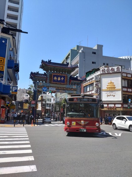 A busy urban street with a red bus, traditional Chinese architecture, and various shops. 2